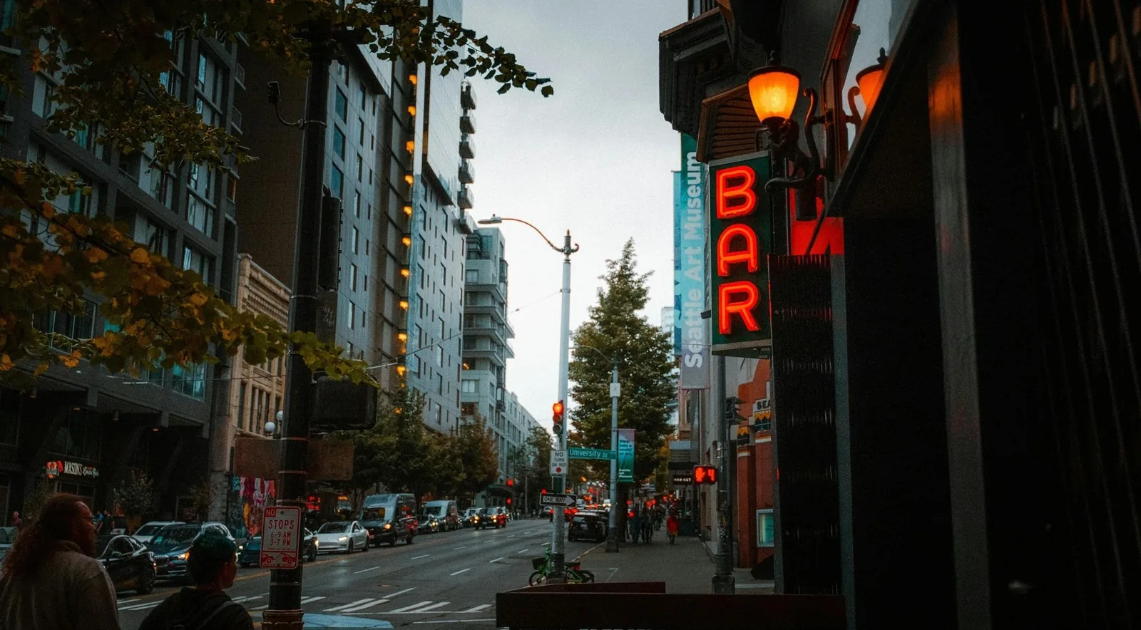 A downtown Seattle street at dusk with neon signs and city lights